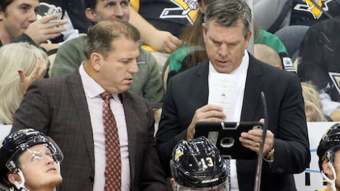 Pittsburgh Penguins assistant coach Mark Recchi (left) and head coach Mike Sullivan (right) look at a replay on a tablet device against the Winnipeg Jets during the second period at PPG PAINTS Arena.