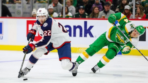 Columbus Blue Jackets defenseman Jake Bean (22) skates with the puck alongside Minnesota Wild center Joel Eriksson Ek (14) during the second period at Xcel Energy Center.