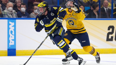 Michigan forward Gavin Brindley (4) and Quinnipiac defenseman Zach Metsa (23) battle fro the puck during the first period in the semifinals of the 2023 Frozen Four college ice hockey tournament at Amalie Arena.