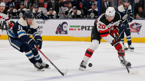 New Jersey Devils center Michael McLeod (20) passes the puck over the stick of Columbus Blue Jackets left wing Kent Johnson (91) during the second period at Nationwide Arena.