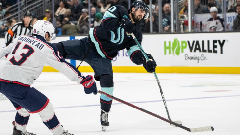 Seattle Kraken forward Matty Beniers (10) takes a shot Columbus Blue Jackets forward Johnny Gaudreau (13) during the second period at Climate Pledge Arena.