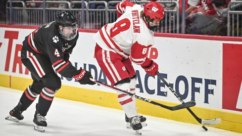 Wisconsin forward William Whitelaw (8) handles the puck behind the net as Northeastern defenseman Pito Walton (4) pursues during the first period of the championship game of the Kwik Trip Holiday Face-Off on Friday, December 29, 2023, at Fiserv Forum in Milwaukee, Wisconsin.