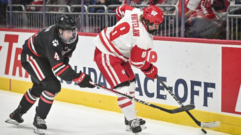 Wisconsin forward William Whitelaw (8) handles the puck behind the net as Northeastern defenseman Pito Walton (4) pursues during the first period of the championship game of the Kwik Trip Holiday Face-Off on Friday, December 29, 2023, at Fiserv Forum in Milwaukee, Wisconsin.