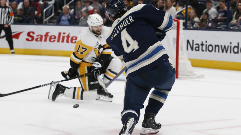 Columbus Blue Jackets forward Cole Sillinger shoots as Bryan Rust drops to block 