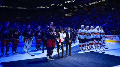 Columbus Blue Jackets center Sean Monahan (23) holds Johnny Gaudreau’s child along side Meredith Gaudreau and family as a banner is raised in honor of Johnny before the home opener at Nationwide Arena.