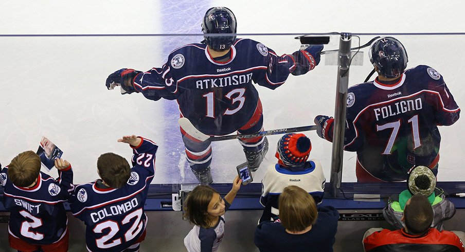 Fans stand behind Cam Atkinson and Nick Foligno of the Columbus Blue Jackets.