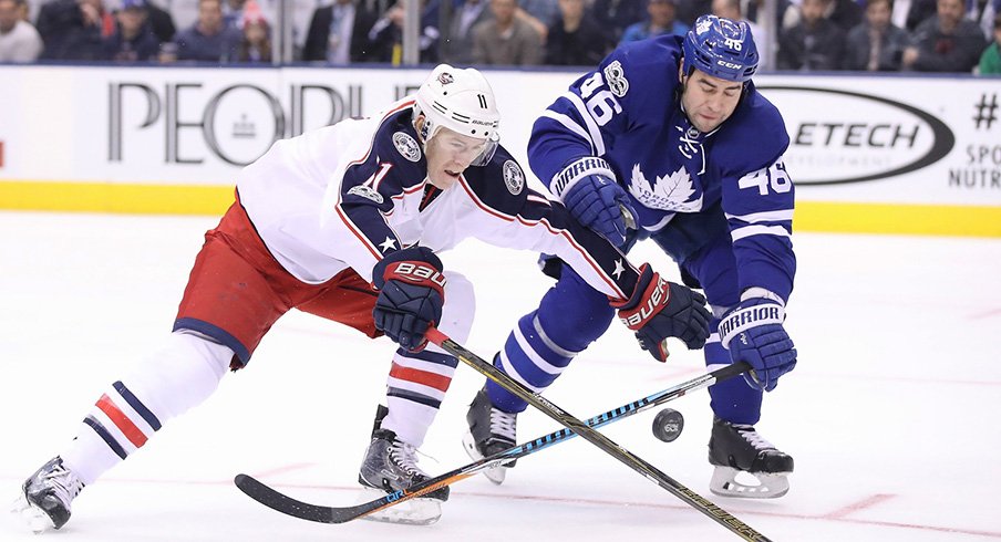 Columbus Blue Jackets left wing Matt Calvert (11) reaches for the puck as Toronto Maple Leafs defenseman Roman Polak (46) goes after the puck at Air Canada Centre.