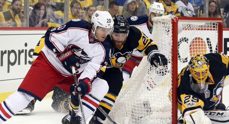 Brandon Saad works his way around the net with Ian Cole draped on his back.