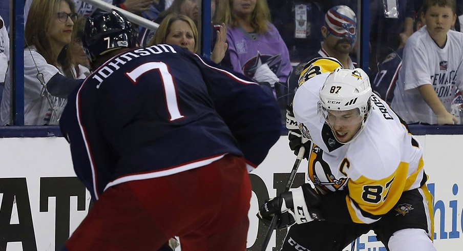 Jack Johnson of the Columbus Blue Jackets meets the Pittsburgh Penguins' Sidney Crosby behind the net.