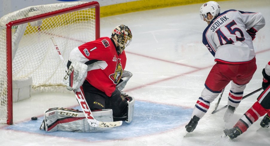 Lukas Sedlak sliding a puck past Mike Condon for a goal