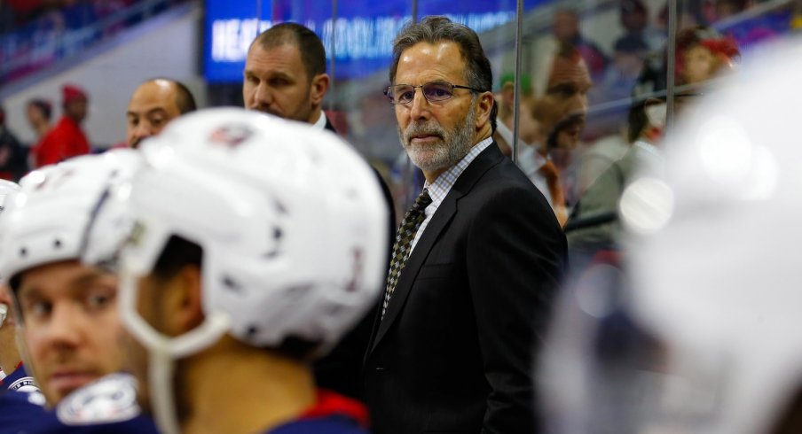 John Tortorella looks thoughtfully off the bench at his players.