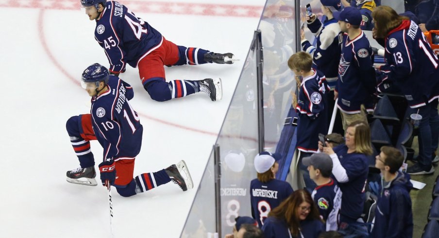 Alexander Wennberg and Lukas Sedlak stretch as fans look on