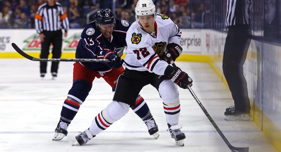 Cam Atkinson tries to push Artemi Panarin off of the puck as he gains the offensive zone.