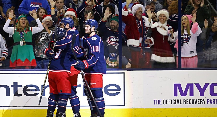 Seth Jones celebrates his goal with his teammates as holiday themed fans look on