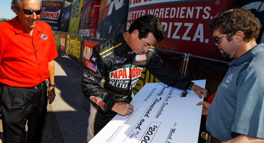 Papa John signs a big check at a racing event