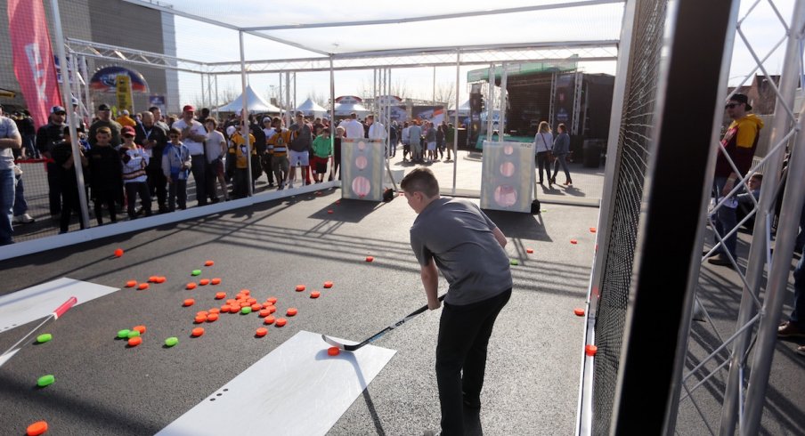 A kid outside the Frozen Four tries his hand at shooting a plastic puck