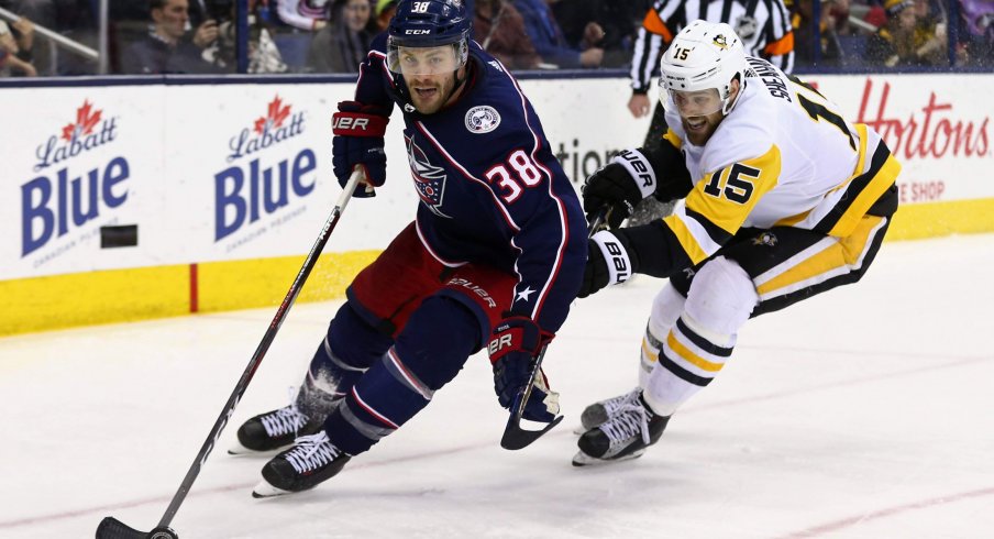 Columbus Blue Jackets forward Boone Jenner skates with the puck against Pittsburgh Penguins forward Riley Sheahan in a game at Nationwide Arena.