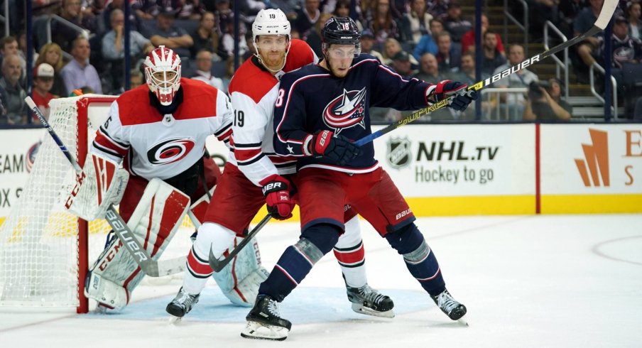 Pierre-Luc Dubois battles with Dougie Hamilton in front of Curtis McElhinney 