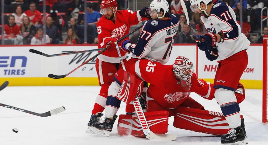 Mike Green checks Josh Anderson into goaltender Jimmy Howard