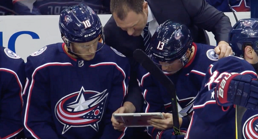 Brad Larsen talks to forwards on the bench before game play starts back up again.