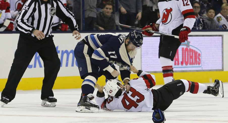 Brandon Dubinsky wrestles a Devils player to the ice.