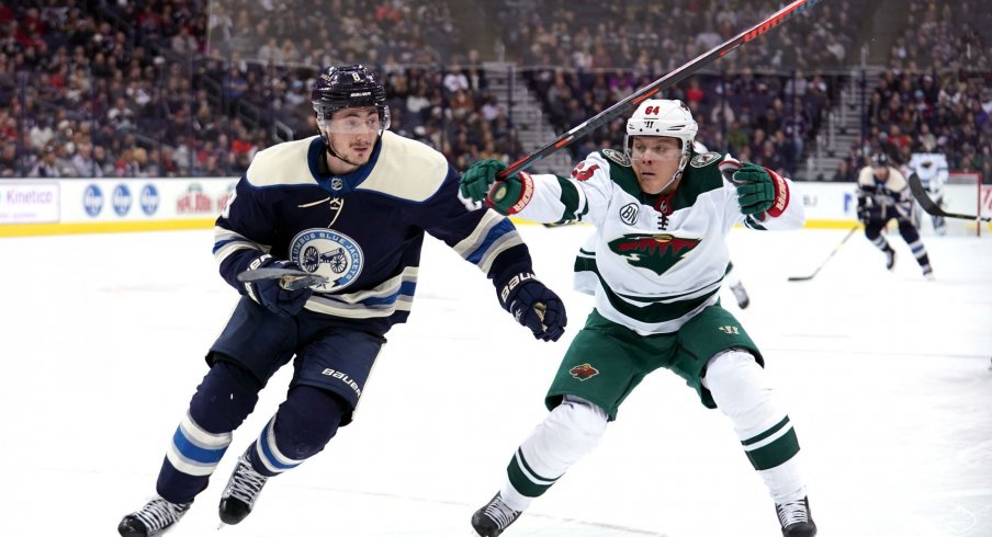 Zach Werenski and Markus Granlund chase after a puck as the Columbus Blue Jackets play the Minnesota Wild