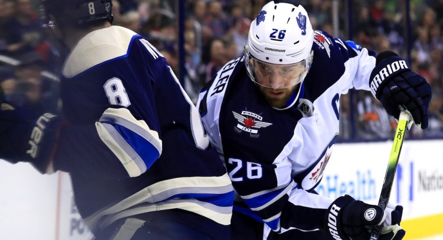 Blake Wheeler tries to rub Zach Werenski out of the play early in the game between the Blue Jackets and Jets.