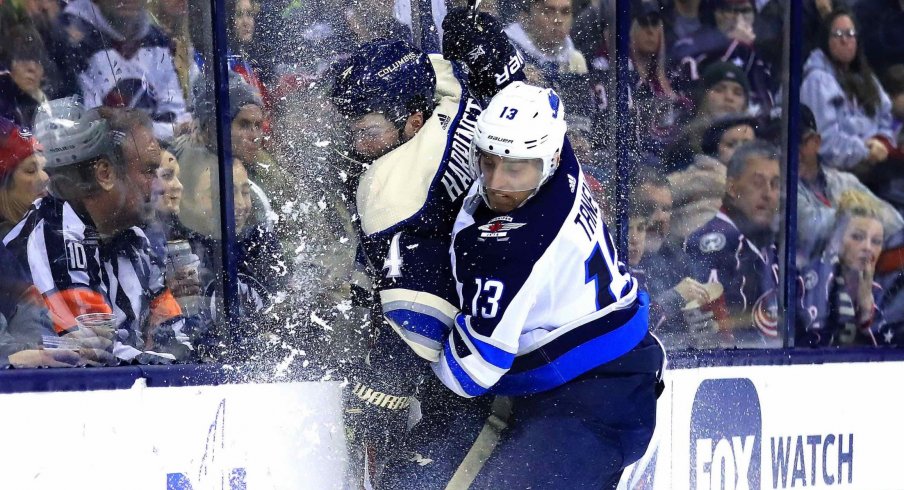 Columbus Blue Jackets defenseman Scott Harrington (4) is checked into the glass by Winnipeg Jets left wing Brandon Tanev (13) in the third period at Nationwide Arena. 