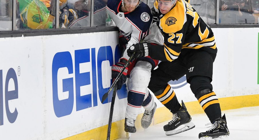 Columbus Blue Jackets center Alexander Wennberg fights for the puck against Boston Bruins defenseman John Moore.