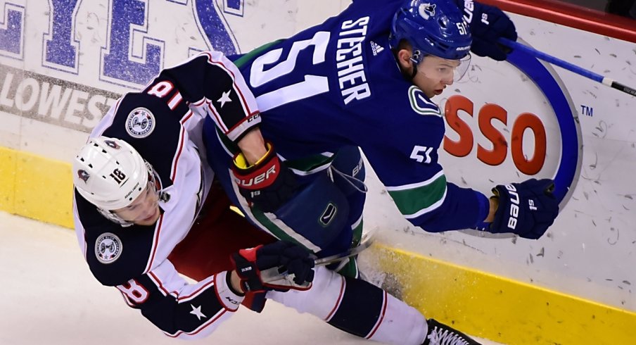 Blue Jackets' Pierre-Luc Dubois fights for the puck against Canucks defenseman Troy Stecher