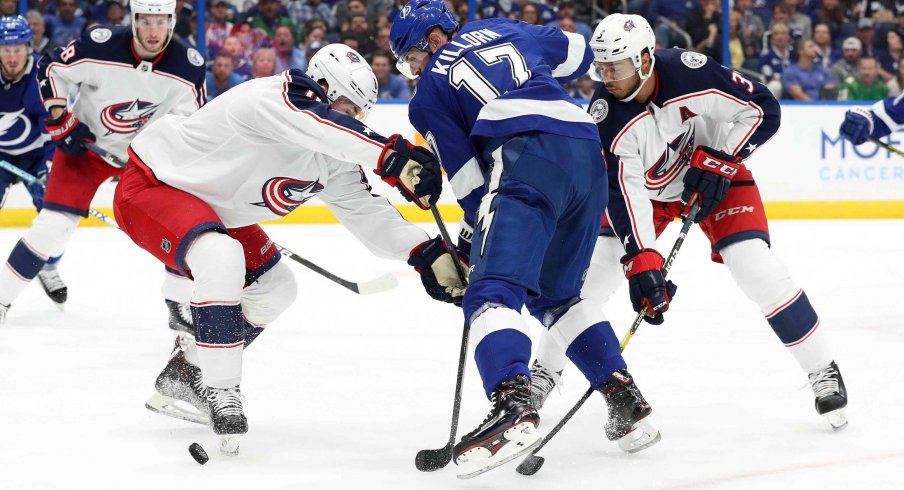 Zach Werenski and Seth Jones tie up Alex Killorn in Game 1 against the Tampa Bay Lightning