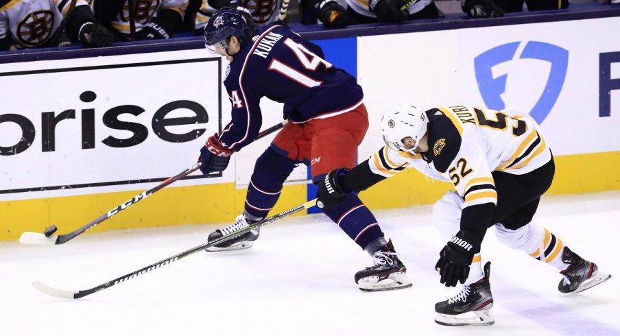 Defenseman Dean Kukan attempts to skate by Boston Bruins forward Sean Kuraly