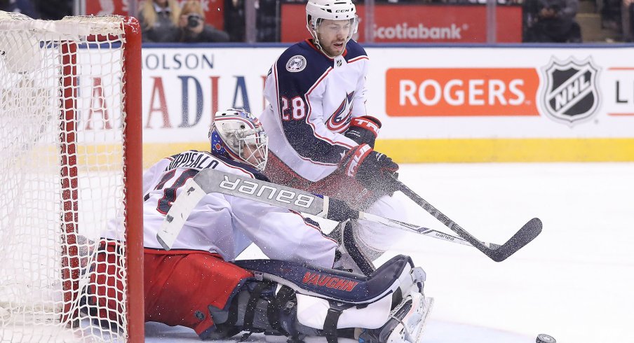 Feb 14, 2018; Toronto, Ontario, CAN; Columbus Blue Jackets goalie Joonas Korpisalo (70) makes a save as right wing Oliver Bjorkstrand (28) goes after the loose puck against the Toronto Maple Leafs at Air Canada Centre. The Maple Leafs beat the Blue Jackets 6-3