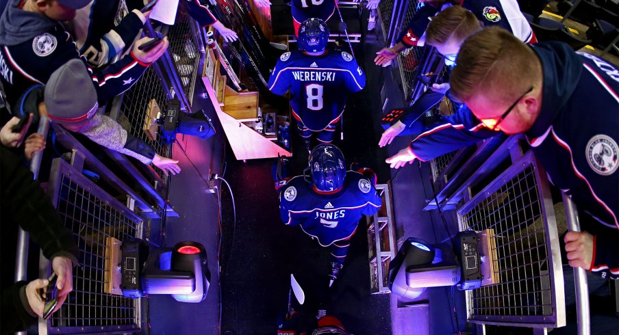 Columbus Blue Jackets defenseman Zach Werenski (8), defenseman Seth Jones (3), and center Pierre-Luc Dubois (18) high fives fans as they take the ice during warmups prior to the game against the Detroit Red Wings at Nationwide Arena.