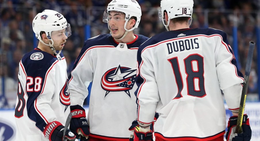 Zach Werenski, Oliver Bjorkstrand, and Pierre-Luc Dubois chat during the second period of game one of the first round of the 2019 Stanley Cup Playoffs against the Tampa Bay Lightning 