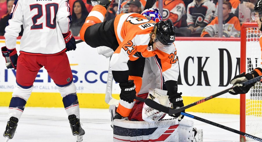 Oct 26, 2019; Philadelphia, PA, USA; Philadelphia Flyers left wing Oskar Lindblom (23) trips over Columbus Blue Jackets goaltender Joonas Korpisalo (70) during the second period at Wells Fargo Center.