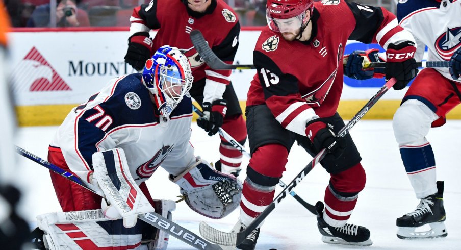 Nov 7, 2019; Glendale, AZ, USA; Arizona Coyotes center Vinnie Hinostroza (13) and Columbus Blue Jackets goaltender Joonas Korpisalo (70) battle for the puck during the second period at Gila River Arena. Mandatory Credit: Matt Kartozian-USA TODAY Sports