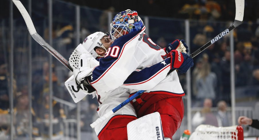 Columbus Blue Jackets goaltender Elvis Merzlikins (90) jumps into the arms of left wing Nick Foligno (71) after defeating the Boston Bruins in overtime at TD Garden.