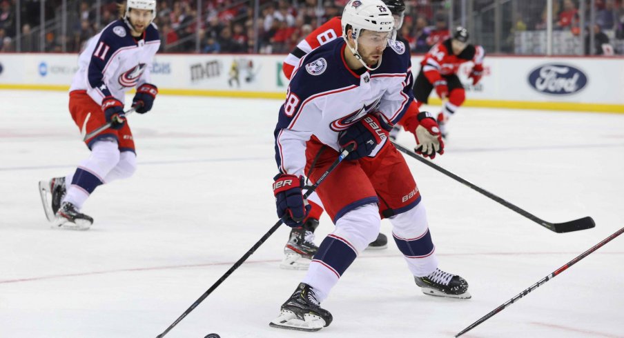 Feb 16, 2020; Newark, New Jersey, USA; Columbus Blue Jackets right wing Oliver Bjorkstrand (28) skates with the puck while being defended by New Jersey Devils defenseman Will Butcher (8) during the first period at Prudential Center.