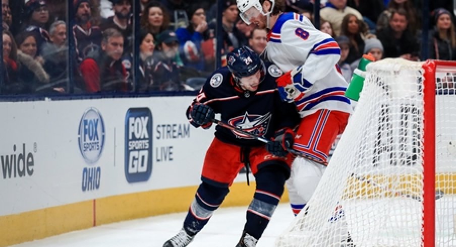 Columbus Blue Jackets forward Nathan Gerbe fights for the puck alongside New York Rangers defenseman Jacob Trouba during a game at Nationwide Arena.