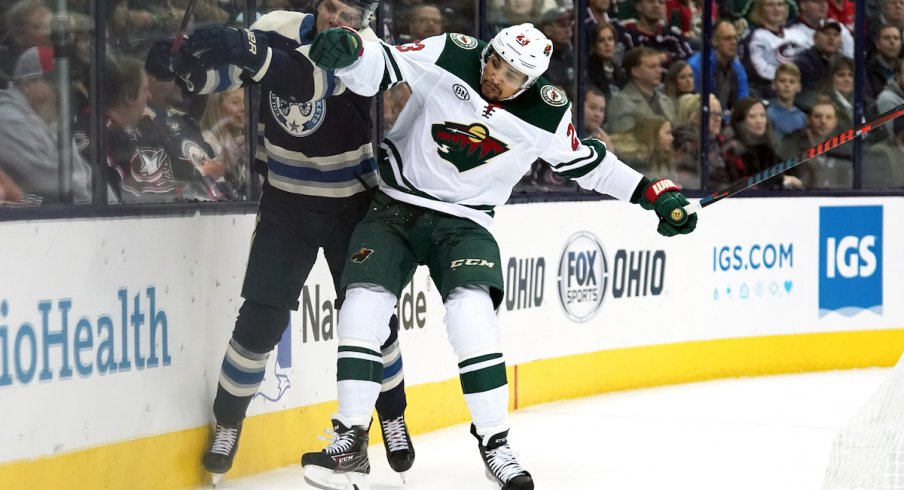 Columbus Blue Jackets defenseman Markus Nutivaara (65) is checked along the boards by Minnesota Wild right wing J.T. Brown (23) in the first period at Nationwide Arena.