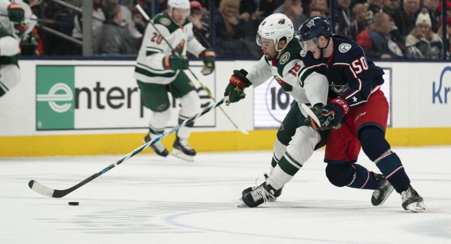 Feb 28, 2020; Columbus, Ohio, USA; Minnesota Wild left wing Jordan Greenway (18) and Columbus Blue Jackets left wing Eric Robinson (50) battle for the puck during the game at Nationwide Arena.