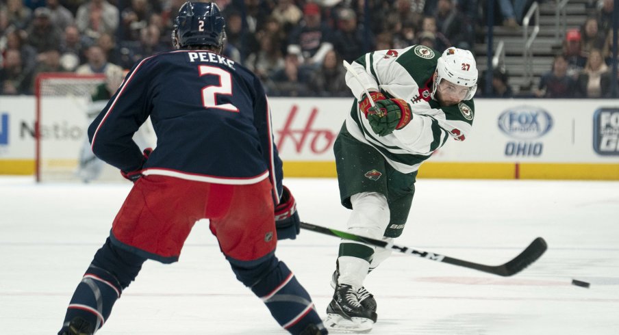 Feb 28, 2020; Columbus, Ohio, USA; Minnesota Wild center Alex Galchenyuk (27) shoots the puck past Columbus Blue Jackets defenseman Andrew Peeke (2) during the game at Nationwide Arena.