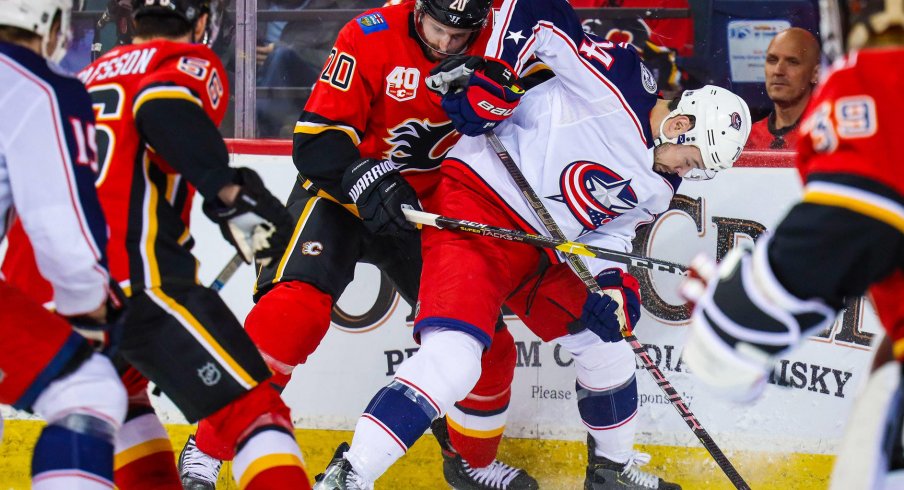 Mar 4, 2020; Calgary, Alberta, CAN; Columbus Blue Jackets center Devin Shore (74) and Calgary Flames defenseman Derek Forbort (20) battle for the puck during the second period at Scotiabank Saddledome. Mandatory Credit: Sergei Belski-USA TODAY Sports