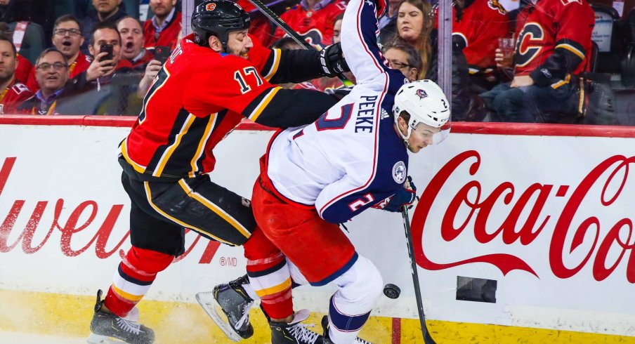 Mar 4, 2020; Calgary, Alberta, CAN; Columbus Blue Jackets defenseman Andrew Peeke (2) and Calgary Flames left wing Milan Lucic (17) battle for the puck during the first period at Scotiabank Saddledome.