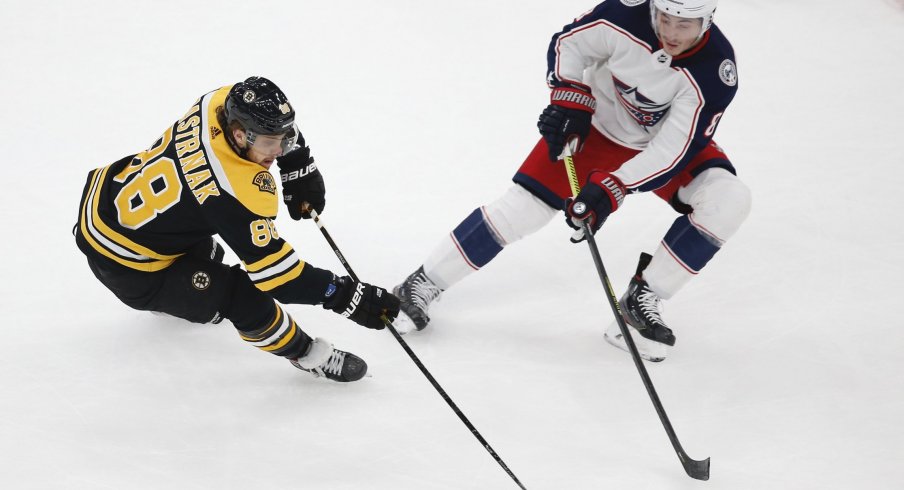 Boston Bruins right wing David Pastrnak (88) keeps the puck away from Columbus Blue Jackets defenseman Zach Werenski (8) during the first period at TD Garden.