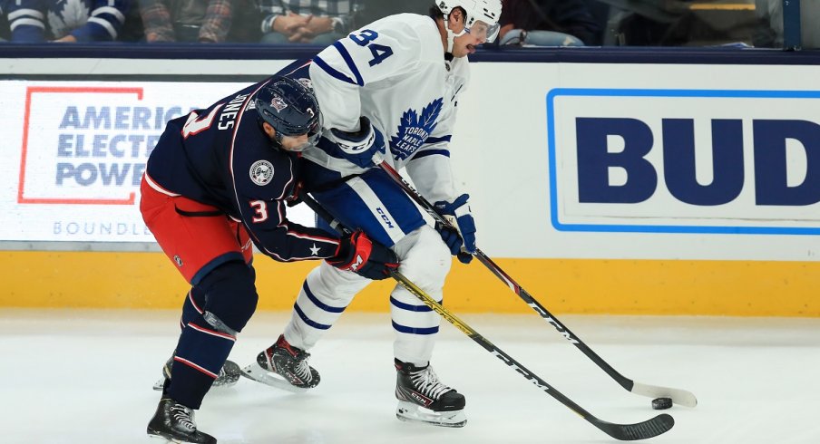 Seth Jones battles for the puck against Auston Matthews 