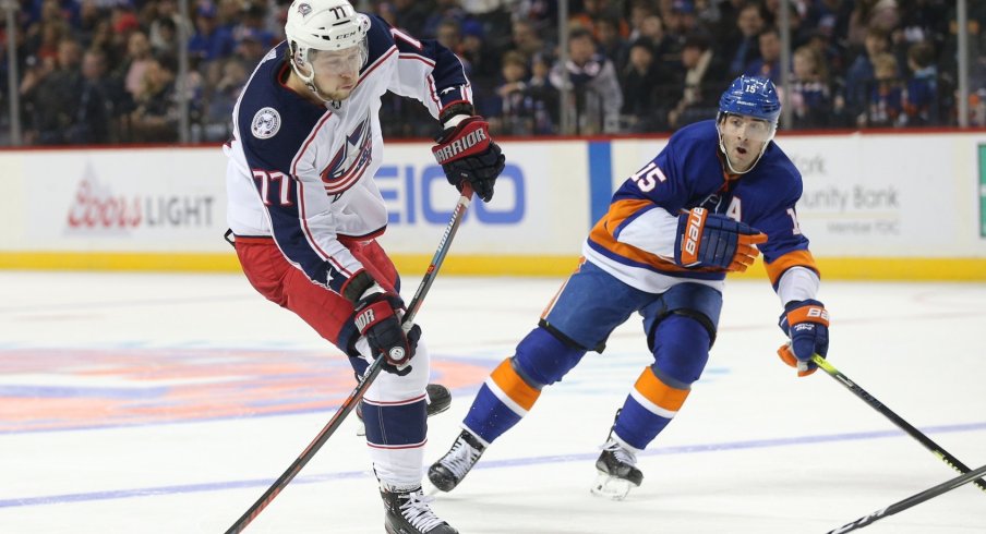 Former Columbus Blue Jacket Josh Anderson tries to get rid of the puck before he is tracked down by Islanders forward Cal Clutterbuck.