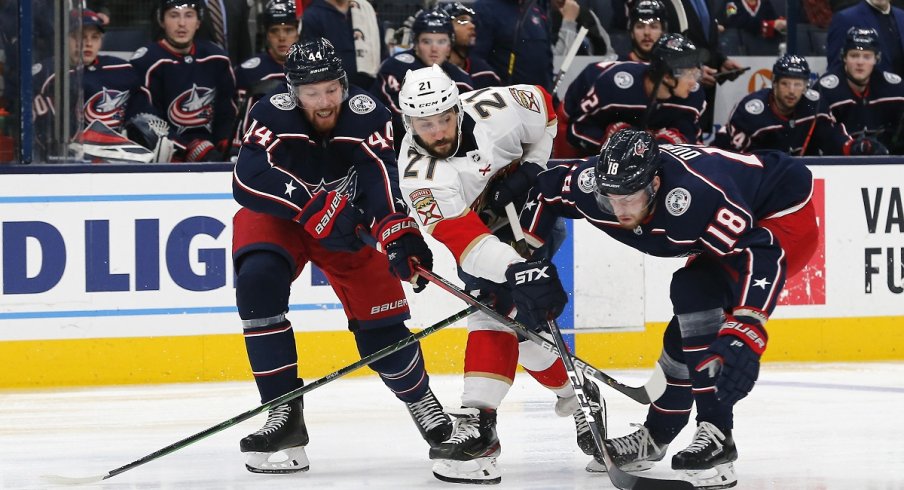 Pierre-Luc Dubois and Vladislav Gavrikov fight for possession with Vincent Trocheck