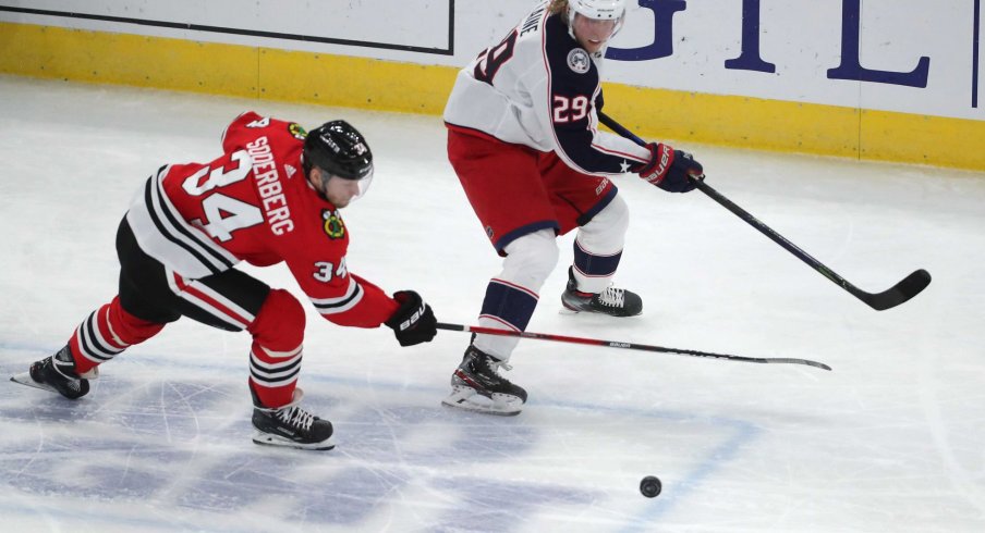 Feb 13, 2021; Chicago, Illinois, USA; Chicago Blackhawks center Carl Soderberg (34) and Columbus Blue Jackets right wing Patrik Laine (29) chase the puck during the third period at the United Center. Chicago won 3-2 in overtime.